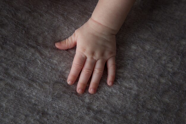Inquadratura dall'alto della mano morbida e paffuta di un bambino su un panno soffice