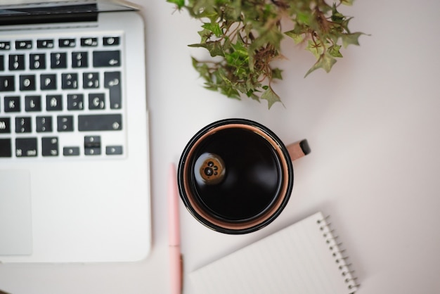 Inquadratura dall'alto della tazza di caffè accanto al laptop argento