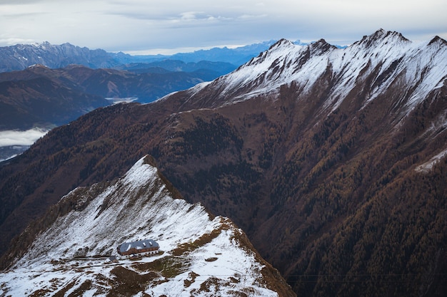 Inquadratura dall'alto di un edificio in cima a una montagna innevata sotto un cielo nuvoloso