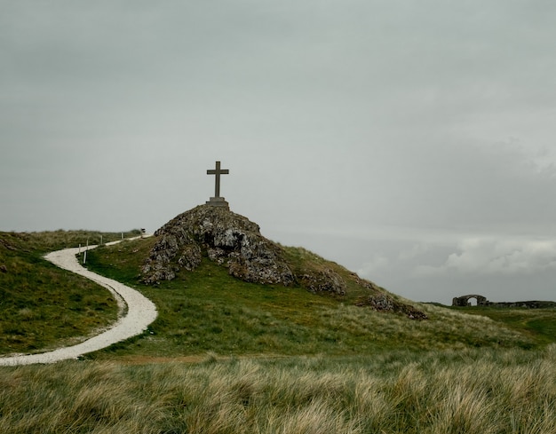 Inquadratura di una croce posta su un piedistallo posto su una collina rocciosa