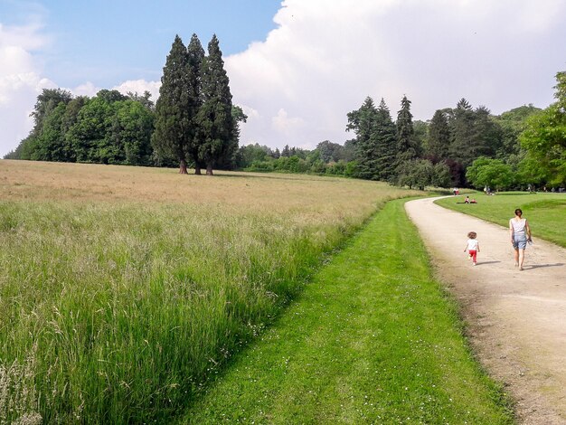 Inquadratura di una donna con un bambino che cammina su un sentiero nel parco in una giornata di sole