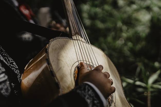 Inquadratura orizzontale di una chitarra acustica beige suonata da un uomo