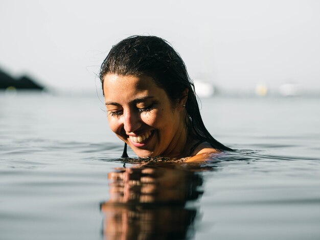 Inquadratura poco profonda di una donna sorridente che nuota in mare