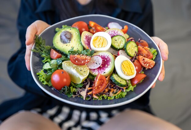 Insalata appetitosa con verdure fresche e uova in un piatto in mani femminili