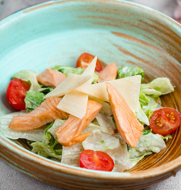 Insalata Caesar con filetto di pesce, lattuga, fette di parmigiano e pomodori tritati.