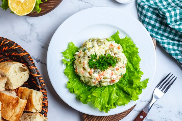 Insalata capitale di vista superiore su lattuga in un piatto con pane in un cestino