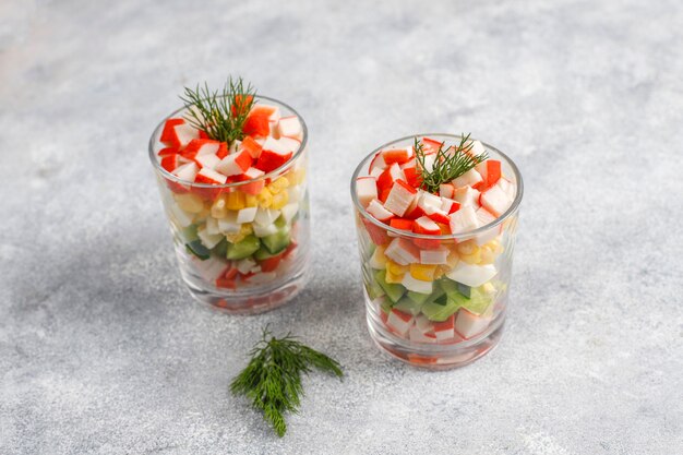 Insalata con bastoncini di granchio, uova, mais e cetriolo.