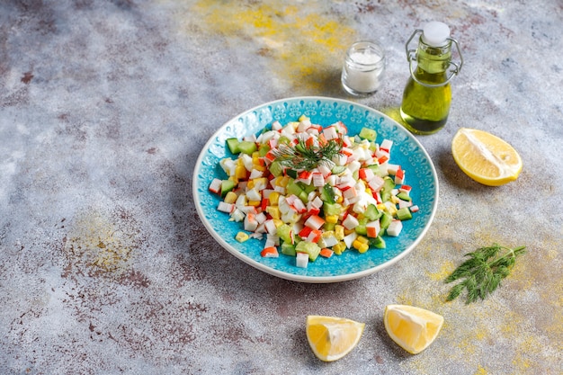 Insalata con bastoncini di granchio, uova, mais e cetriolo.