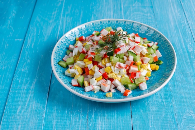 Insalata con bastoncini di granchio, uova, mais e cetriolo.