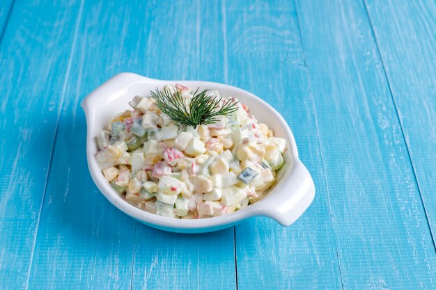 Insalata con bastoncini di granchio, uova, mais e cetriolo.