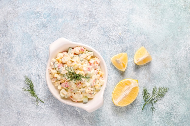 Insalata con bastoncini di granchio, uova, mais e cetriolo.