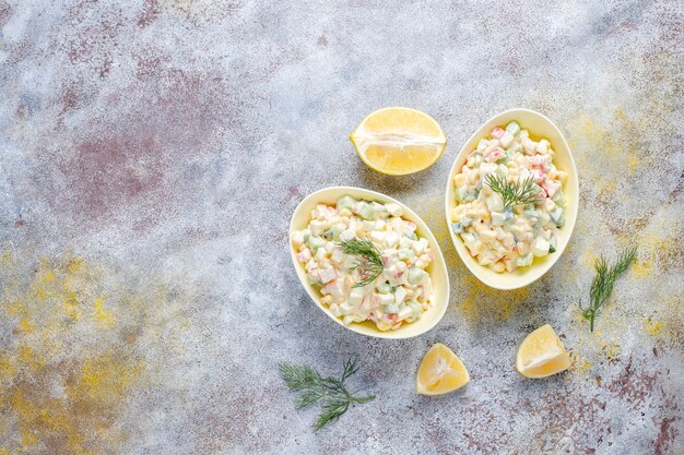 Insalata con bastoncini di granchio, uova, mais e cetriolo.