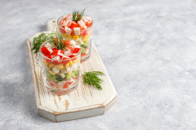 Insalata con bastoncini di granchio, uova, mais e cetriolo.