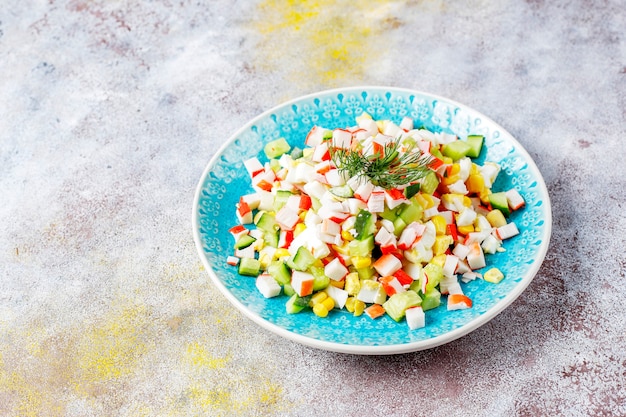 Insalata con bastoncini di granchio, uova, mais e cetriolo.