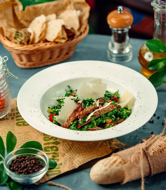 Insalata con erbe verdi, filetto di pollo e parmigiano tritato.