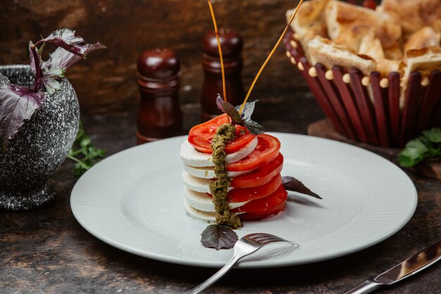 Insalata con mozzarella e fettine di pomodoro condite con basilico ed erbe.