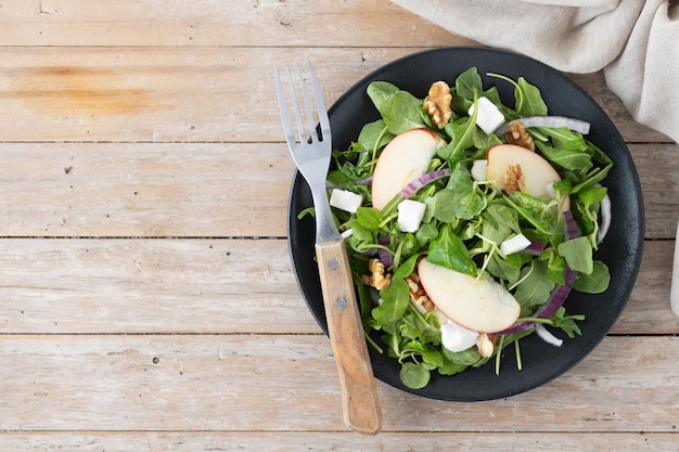 Insalata d'autunno con mele e noci su un tavolo di legno