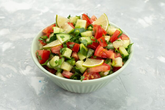 Insalata della verdura fresca di vista frontale con le verdure e le fette affettate del limone dentro il piatto rotondo sull'azzurro, verdura di insalata del pasto dell'alimento