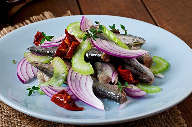 Insalata di aringhe con pomodori secchi, sedano e cipolla rossa