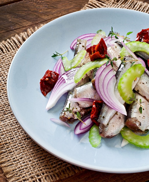 Insalata di aringhe con pomodori secchi, sedano e cipolla rossa