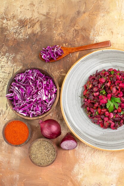 Insalata di barbabietole vista dall'alto sulla base di cipolle rosse cavolo tritato curcuma e pepe macinato in un piatto di ceramica grigia su uno sfondo di legno con spazio di copia