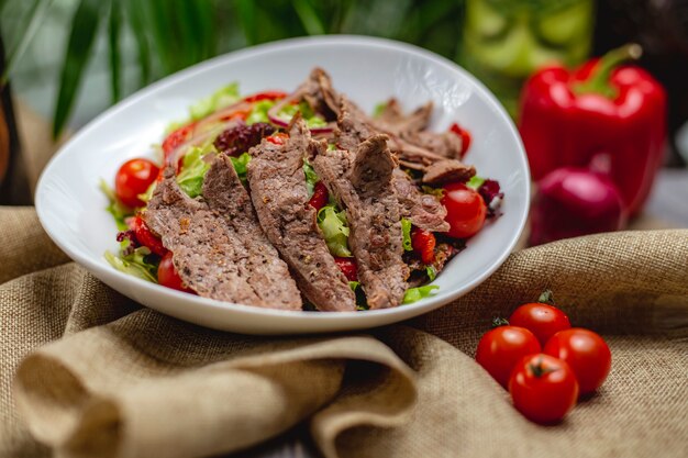 Insalata di carne con manzo, pomodorini, lattuga e cipolla rossa in un piatto bianco