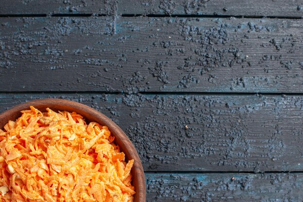 Insalata di carote grattugiate vista dall'alto all'interno del piatto su insalata da scrivania rustica blu scuro colore verdure dietetiche mature per la salute