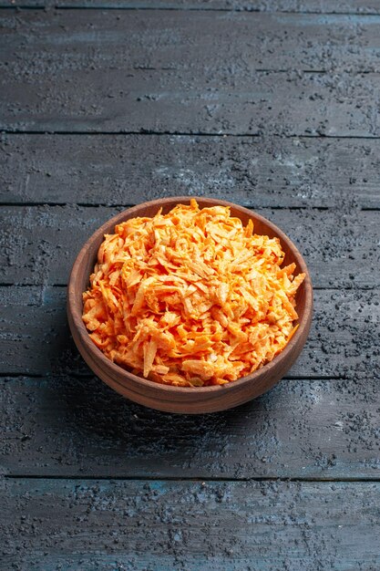 Insalata di carote grattugiate vista frontale all'interno del piatto sull'insalata da scrivania rustica blu scuro colore maturo dieta salute vegetale