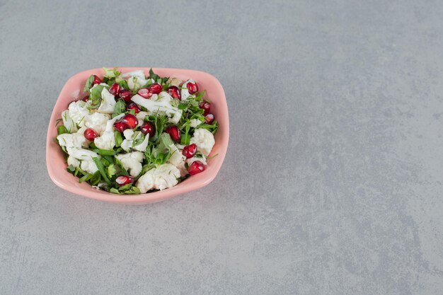 Insalata di cavolfiore nel piatto con semi di melograno ed erbe aromatiche.