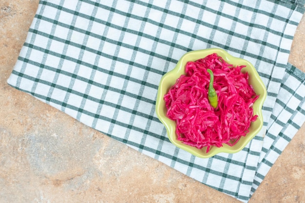 Insalata di crauti rossi in una ciotola verde con tovaglia.