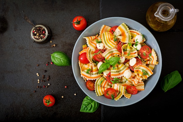 Insalata di farfalle di pasta colorata con pomodori, mozzarella e basilico.