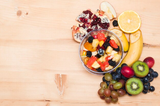 Insalata di frutta con i frutti su fondo strutturato di legno