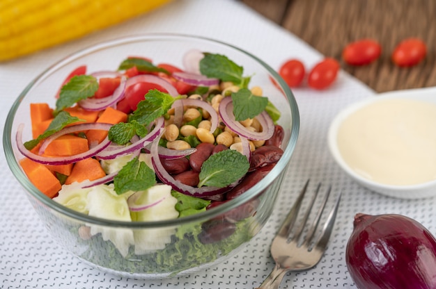 Insalata di frutta e verdura in una tazza di vetro su una terra bianca