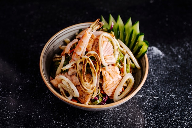 Insalata di mare con salmone fille, granchi e verdure all'interno della ciotola.