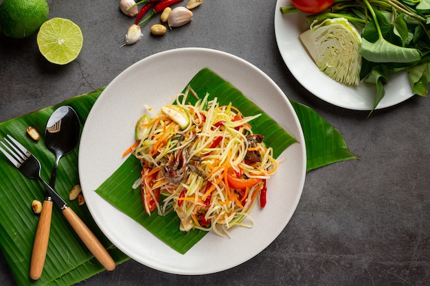 Insalata di papaya servita con spaghetti di riso e insalata di verdure Decorata con ingredienti alimentari tailandesi.