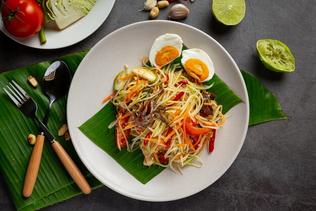 Insalata di papaya servita con spaghetti di riso e insalata di verdure Decorata con ingredienti alimentari tailandesi.