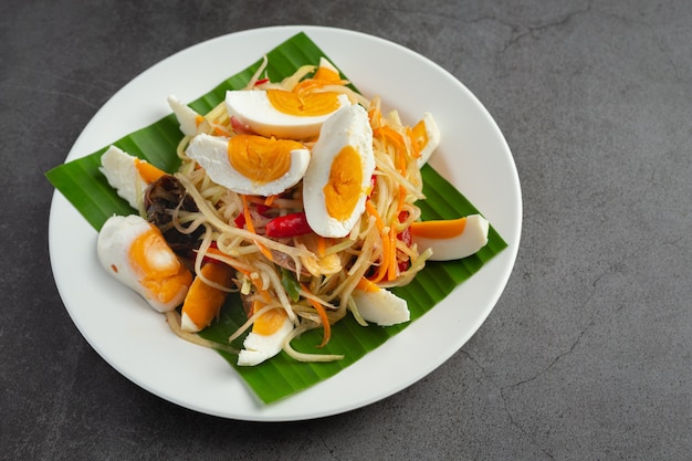 Insalata di papaya servita con spaghetti di riso e insalata di verdure Decorata con ingredienti alimentari tailandesi.