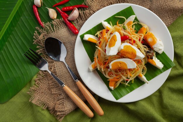 Insalata di papaya servita con spaghetti di riso e insalata di verdure Decorata con ingredienti alimentari tailandesi.