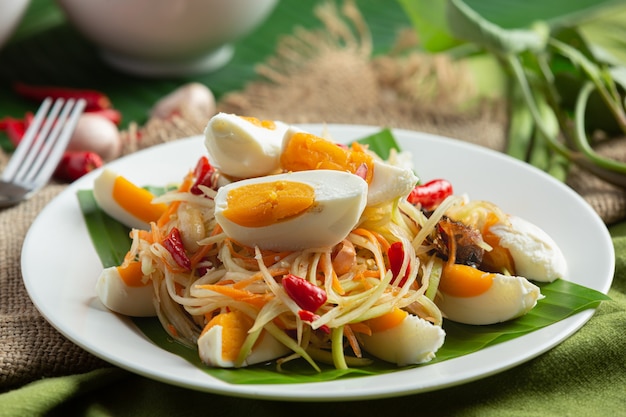 Insalata di papaya servita con spaghetti di riso e insalata di verdure Decorata con ingredienti alimentari tailandesi.