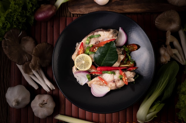 Insalata di pesce con lime, peperoncino, citronella, cipolle, cipolle rosse, prezzemolo e foglie di lime kaffir nel piatto