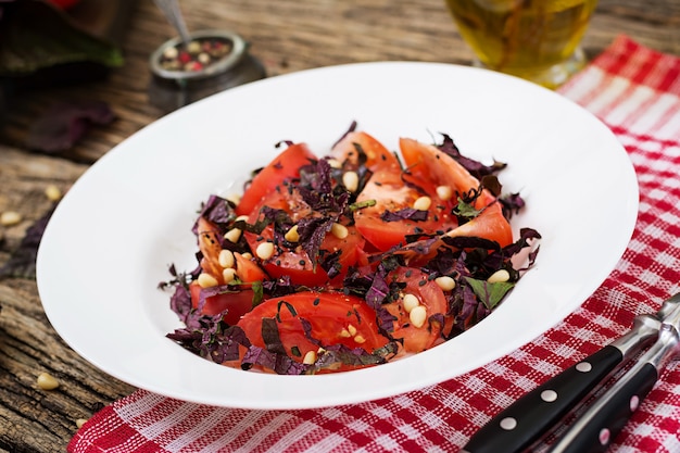 Insalata di pomodori con basilico viola e pinoli. Cibo vegano. Pasto italiano.