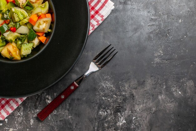 Insalata di pomodori verdi a metà vista dall'alto su piatto ovale una forchetta su sfondo scuro