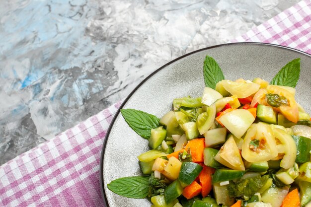 Insalata di pomodori verdi con vista a metà superiore su tovaglia rosa piatto ovale su sfondo grigio