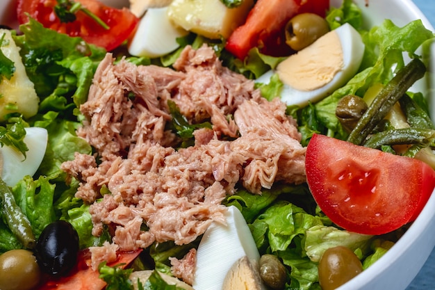 Insalata di tonno vista laterale con uovo sodo pomodoro fresco verde oliva e capperi sott'aceto