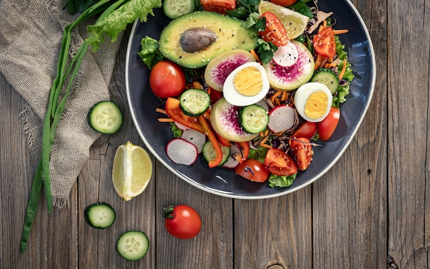 Insalata di verdure appetitosa con uova di avocado su fondo di legno