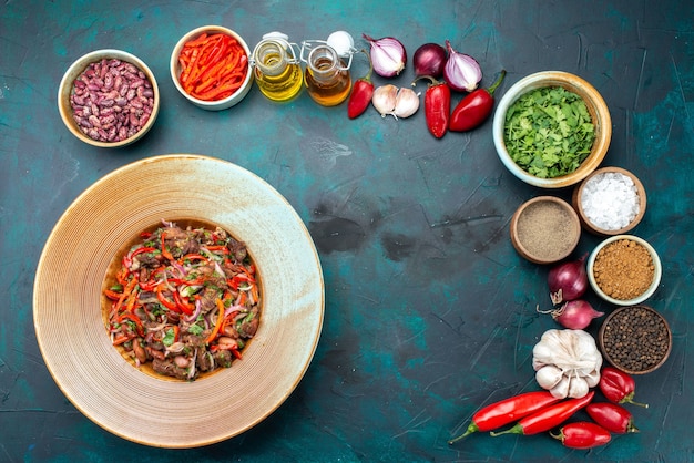 Insalata di verdure carnosa vista in lontananza all'interno del piatto insieme a verdure verdure verdi sulla scrivania blu scuro, insalata di ingredienti alimentari