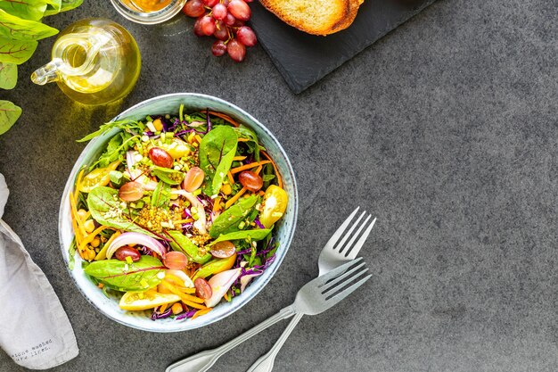 Insalata di verdure e frutta fresche in un piatto su uno sfondo di pietra nera