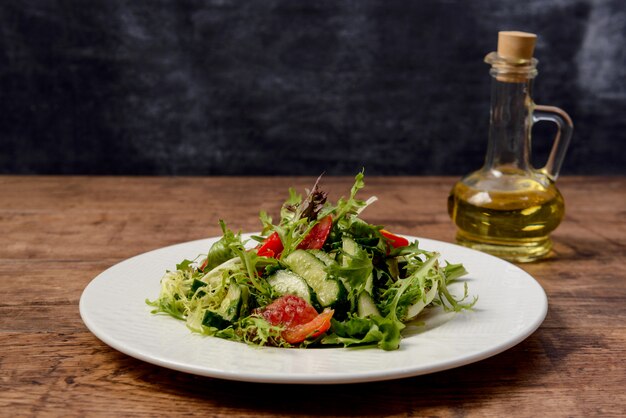 Insalata di verdure in piatto rotondo bianco sulla tavola di legno.