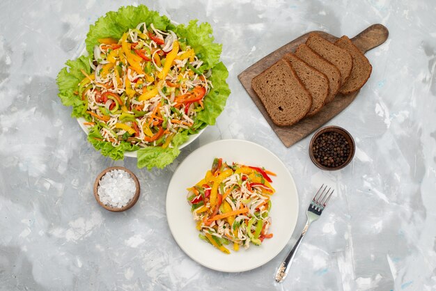 Insalata di verdure saporita di vista superiore con le verdure affettate e insalata verde con le pagnotte di pane sul pasto dell'alimento dell'insalata grigia e di verdure