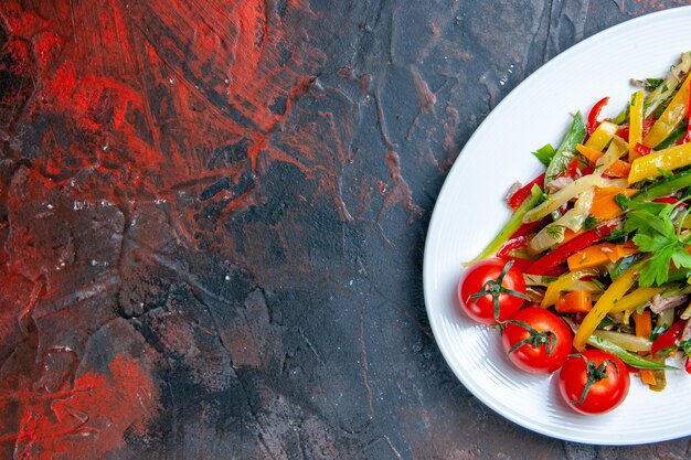 Insalata di verdure vista metà superiore su piatto ovale su spazio libero superficie rosso scuro